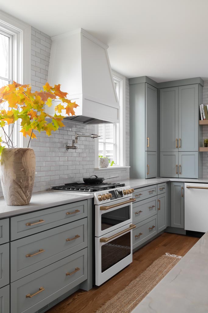 Luxury kitchen with sage green cabinetry, brass hardware, white subway tile backsplash, and natural wood accents in Ann Arbor, Michigan.