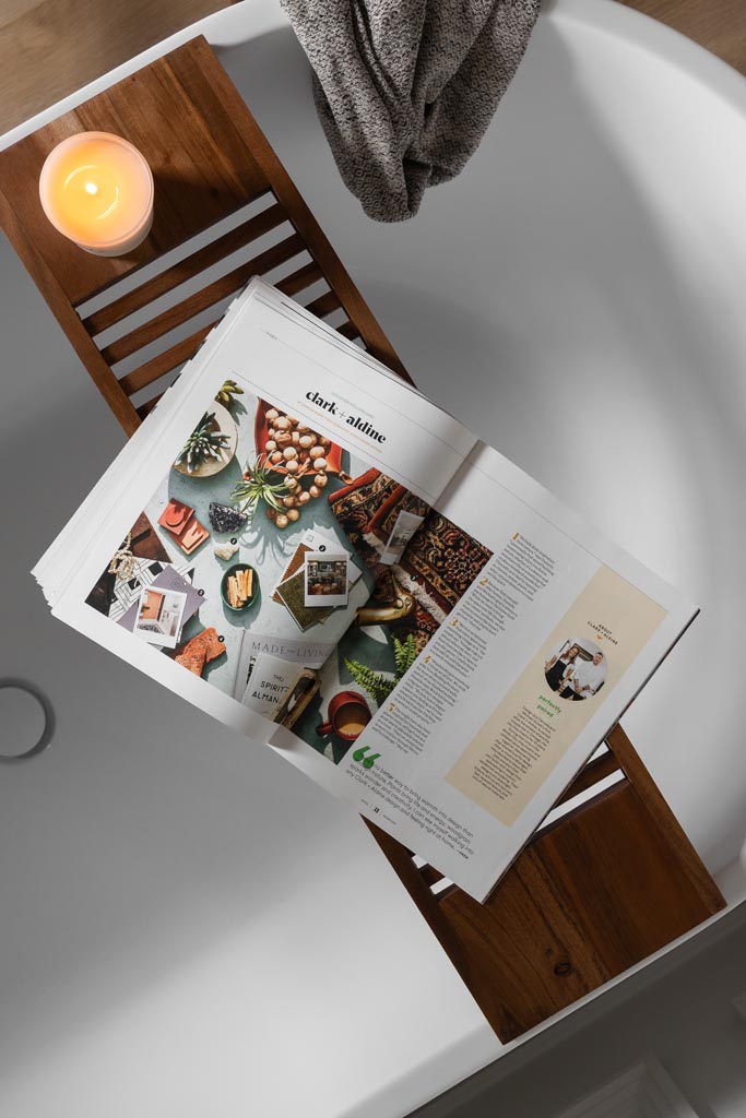 Overhead view of a bathtub styled with a wooden bath tray, book, and candle in a Canton, MI bathroom renovation.