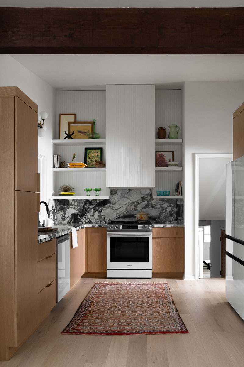Dynamic kitchen design in Royal Oak, MI, featuring a striking marble backsplash, natural wood cabinets, and curated decor.