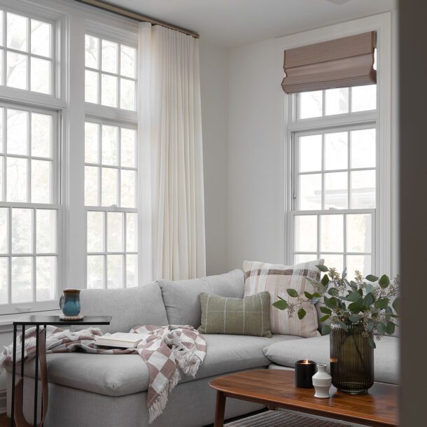 Construction and remodeling by Clark + Aldine – a biophilic living room with natural light, featuring a gray sectional, wood coffee table, indoor plants, and nature-inspired decor in neutral tones, ready for move-in.