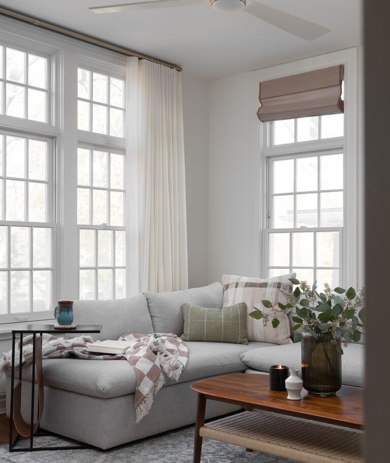 Construction and remodeling by Clark + Aldine – a biophilic living room with natural light, featuring a gray sectional, wood coffee table, indoor plants, and nature-inspired decor in neutral tones, ready for move-in.