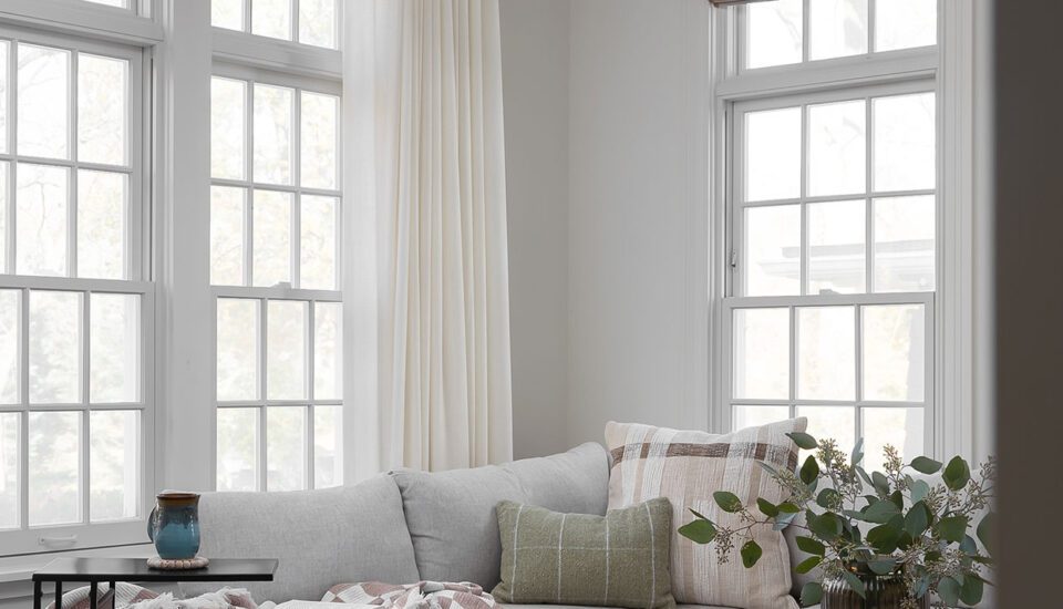 Construction and remodeling by Clark + Aldine – a biophilic living room with natural light, featuring a gray sectional, wood coffee table, indoor plants, and nature-inspired decor in neutral tones, ready for move-in.