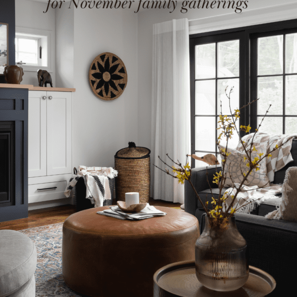 A warm, inviting living room with natural textures and cozy seating, perfect for November family gatherings. Features a leather ottoman, patterned area rug, and nature-inspired decor.