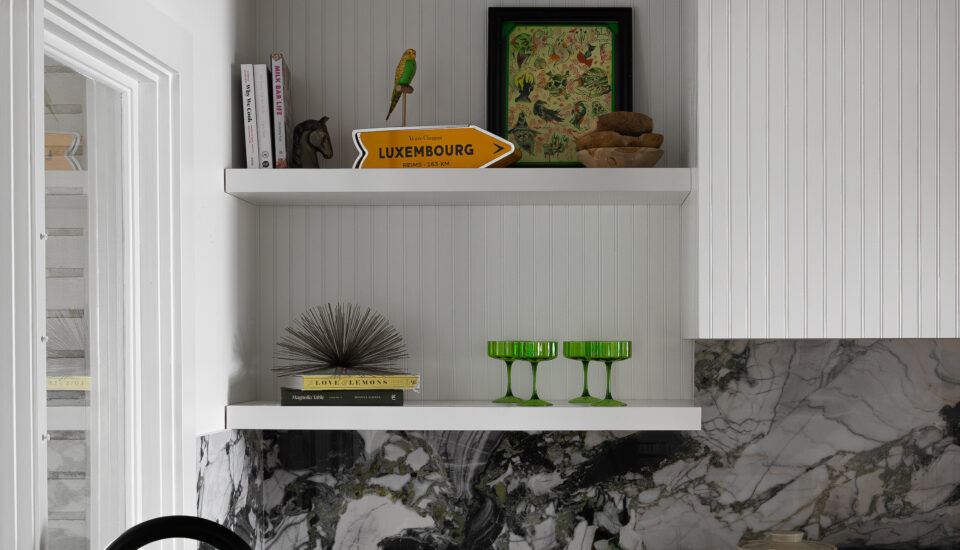 A luxurious modern kitchen with striking marble countertops and backsplash, open shelving with eclectic decor, and a matte black faucet. This kitchen design combines high-end materials with unique decorative accents, creating a visually captivating space. Perfect for homeowners seeking inspiration to elevate their modern luxury kitchen design.