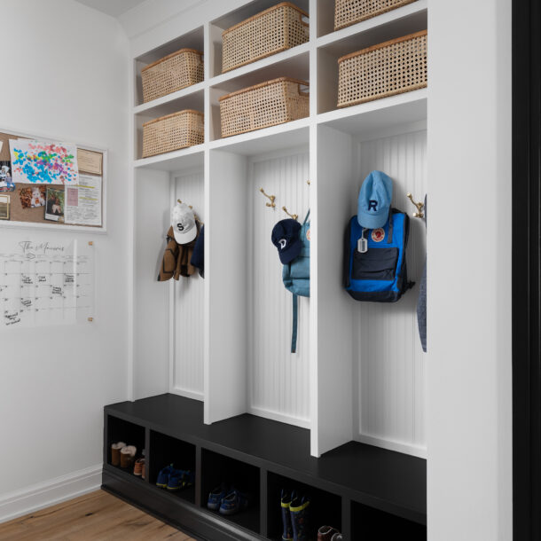 Functional mudroom featuring individual cubbies with hooks for backpacks and hats, woven baskets for storage, and cubby spaces for shoes, creating an organized and family-friendly entryway.