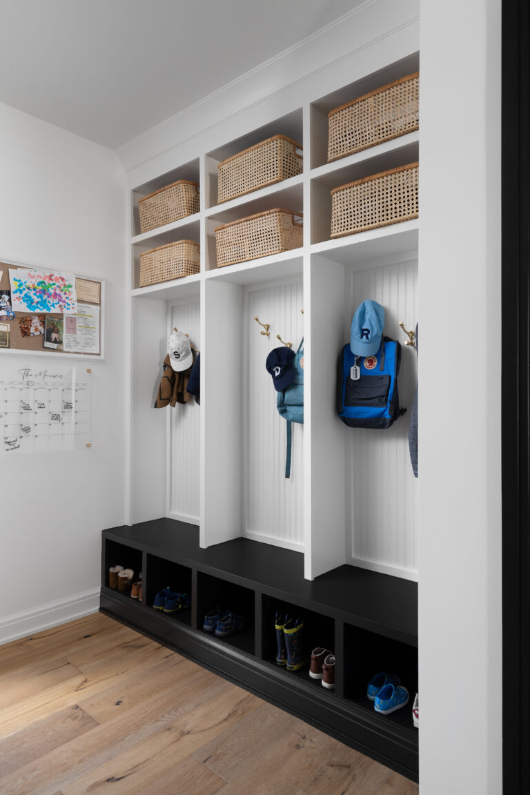 Functional mudroom featuring individual cubbies with hooks for backpacks and hats, woven baskets for storage, and cubby spaces for shoes, creating an organized and family-friendly entryway.
