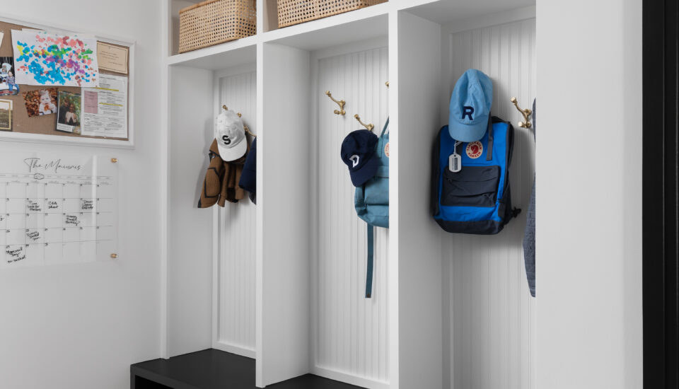 Functional mudroom featuring individual cubbies with hooks for backpacks and hats, woven baskets for storage, and cubby spaces for shoes, creating an organized and family-friendly entryway.