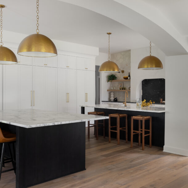 High-end kitchen in Plymouth, MI, featuring custom white cabinetry, quartzite countertops, brass pendant lighting, and a spacious island.